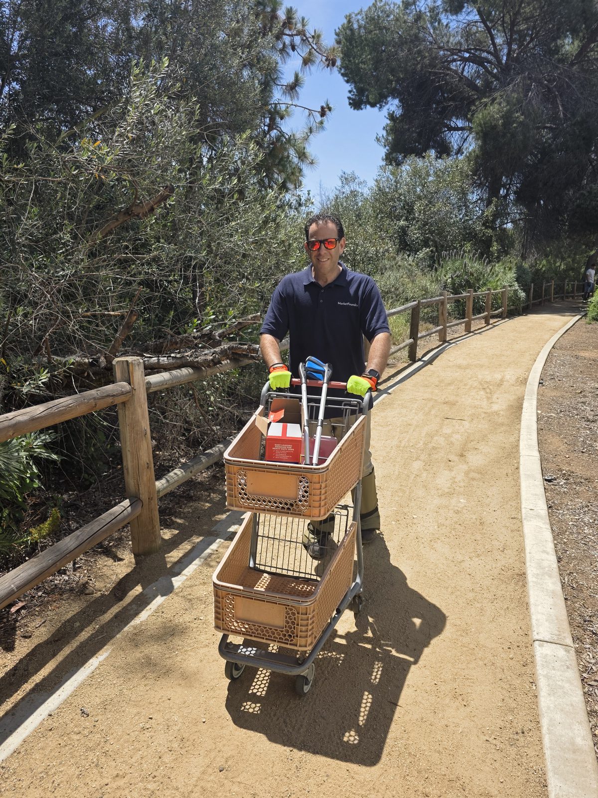 Crew member pushing recovered shopping cart on trail
